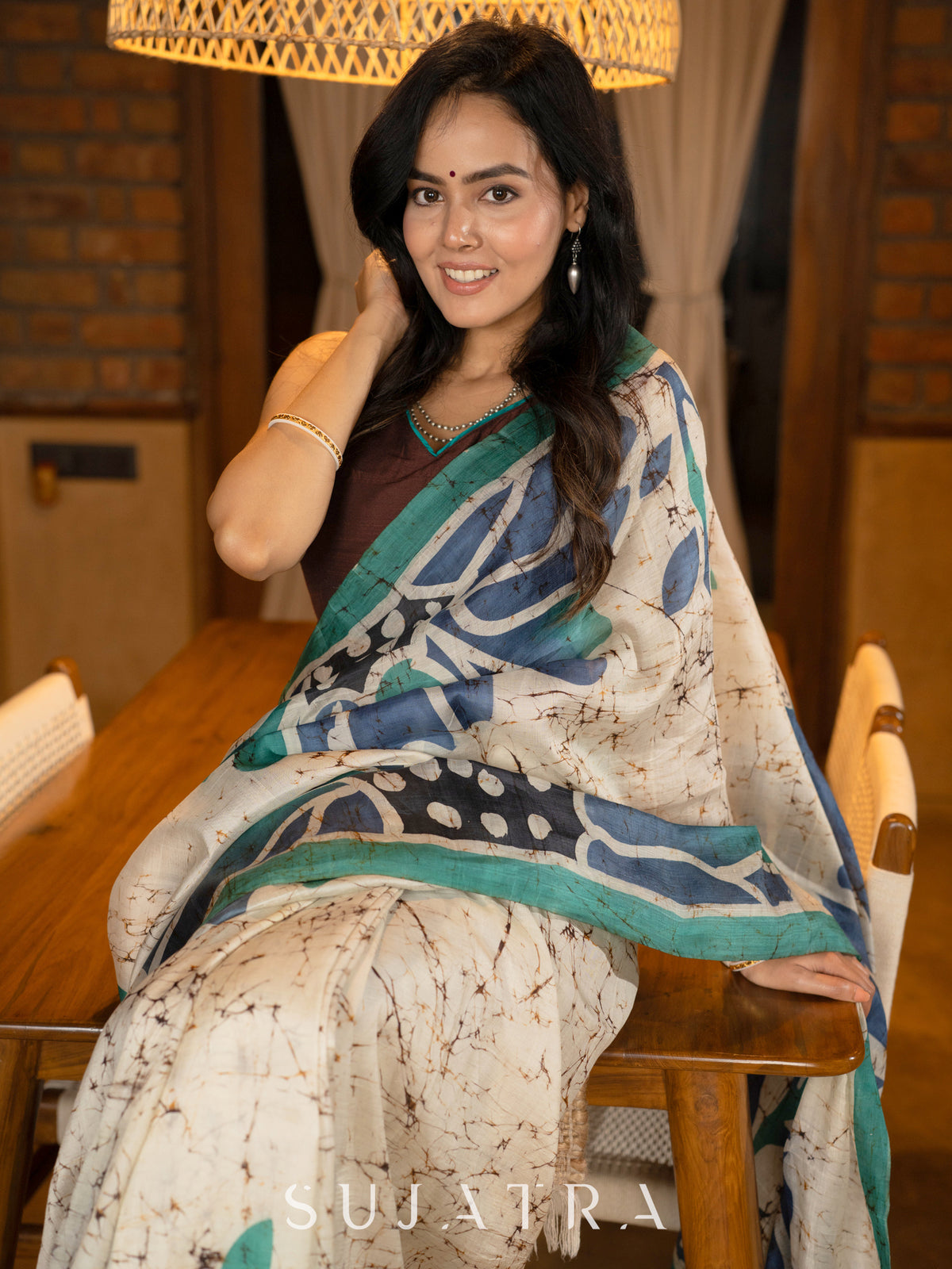 Classic ivory pure silk saree highlighted by teal borders and hand batik artistry