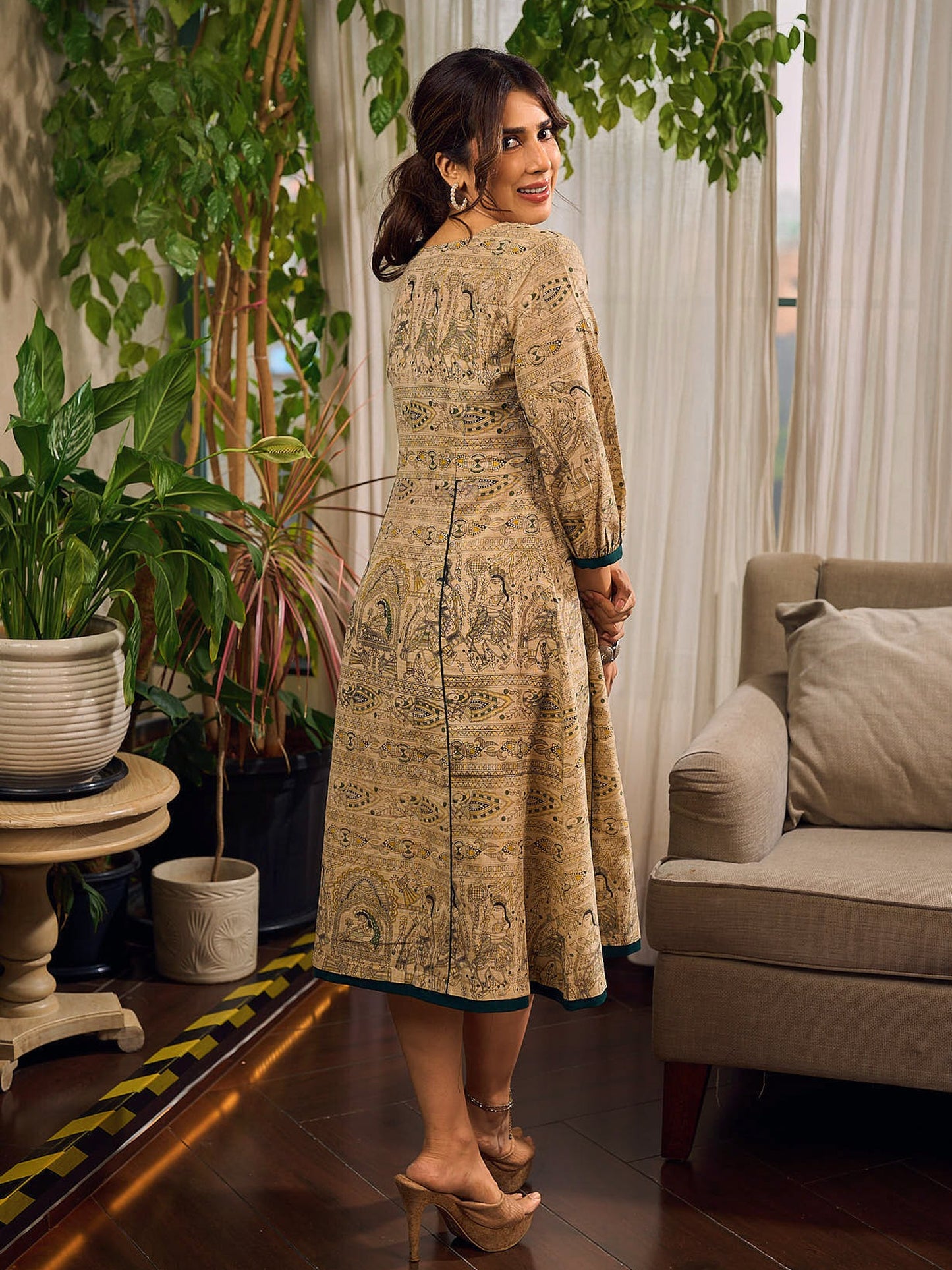 Artisanal beige Madhubani dress featuring intricate motifs, a contrasting green yoke, and refined accents.