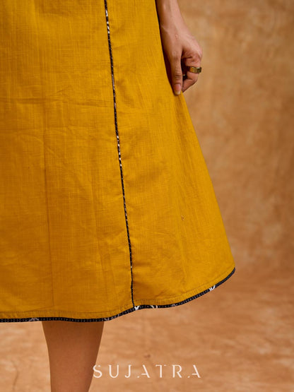 Warm mustard one-piece dress with panelled construction for fluid movement, a sleeveless silhouette, and Kantha cord piping, offering a graceful, well-defined shape with subtle texture and refined detail.