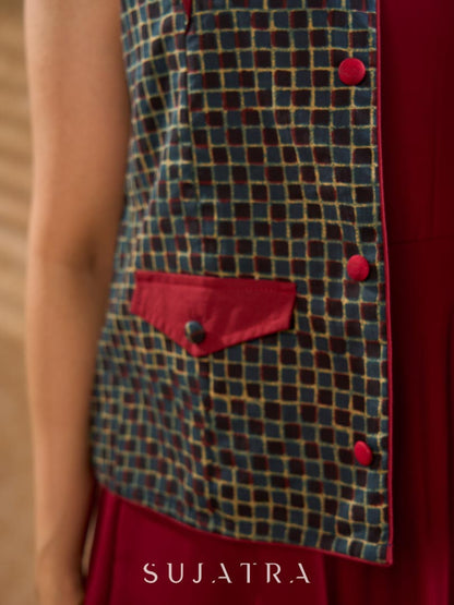 Sharp dark teal and maroon checkered sleeveless jacket with a distinctive notch collar and princess-cut tailoring, offering a structured silhouette ideal for elevated corporate styling.