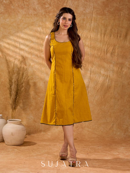 Warm mustard one-piece dress with panelled construction for fluid movement, a sleeveless silhouette, and Kantha cord piping, offering a graceful, well-defined shape with subtle texture and refined detail.