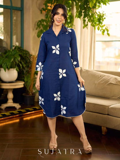 Navy blue apple-cut shirt dress with white floral hand block motifs, conceptually placed and finished with clean white edging and red accents for a refined, contemporary look.