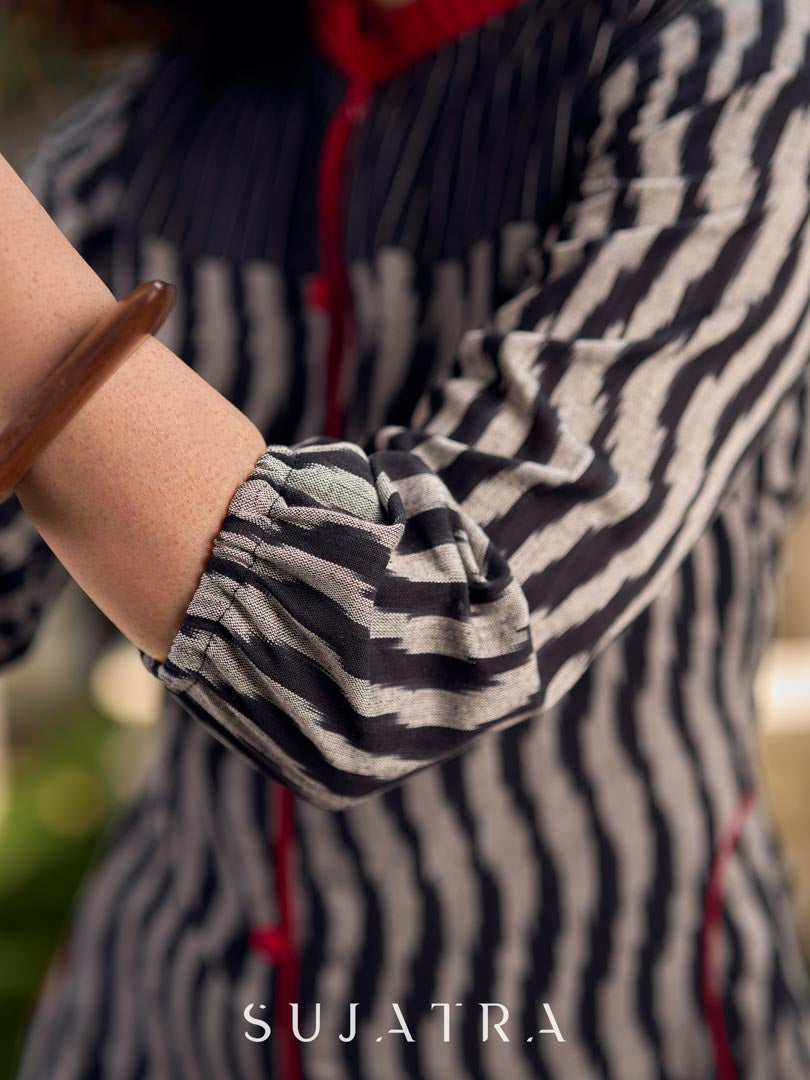 Black grey Ikat dress with soft frill detailing at the neckline, accented with red highlights, and finished with gentle gathers toward the bottom for a fluid silhouette