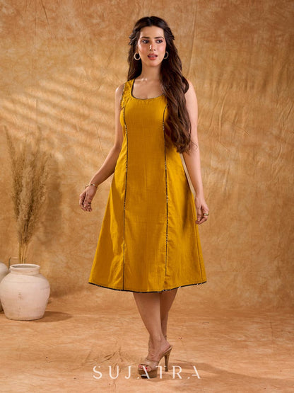 Warm mustard one-piece dress with panelled construction for fluid movement, a sleeveless silhouette, and Kantha cord piping, offering a graceful, well-defined shape with subtle texture and refined detail.