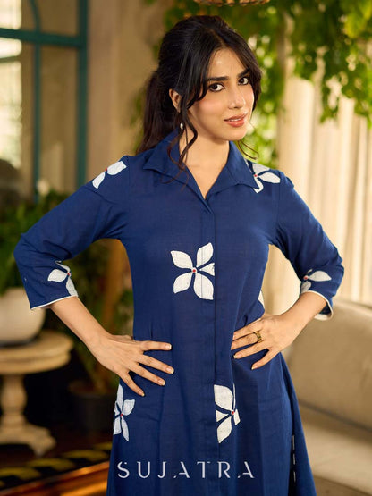 Navy blue apple-cut shirt dress with white floral hand block motifs, conceptually placed and finished with clean white edging and red accents for a refined, contemporary look.