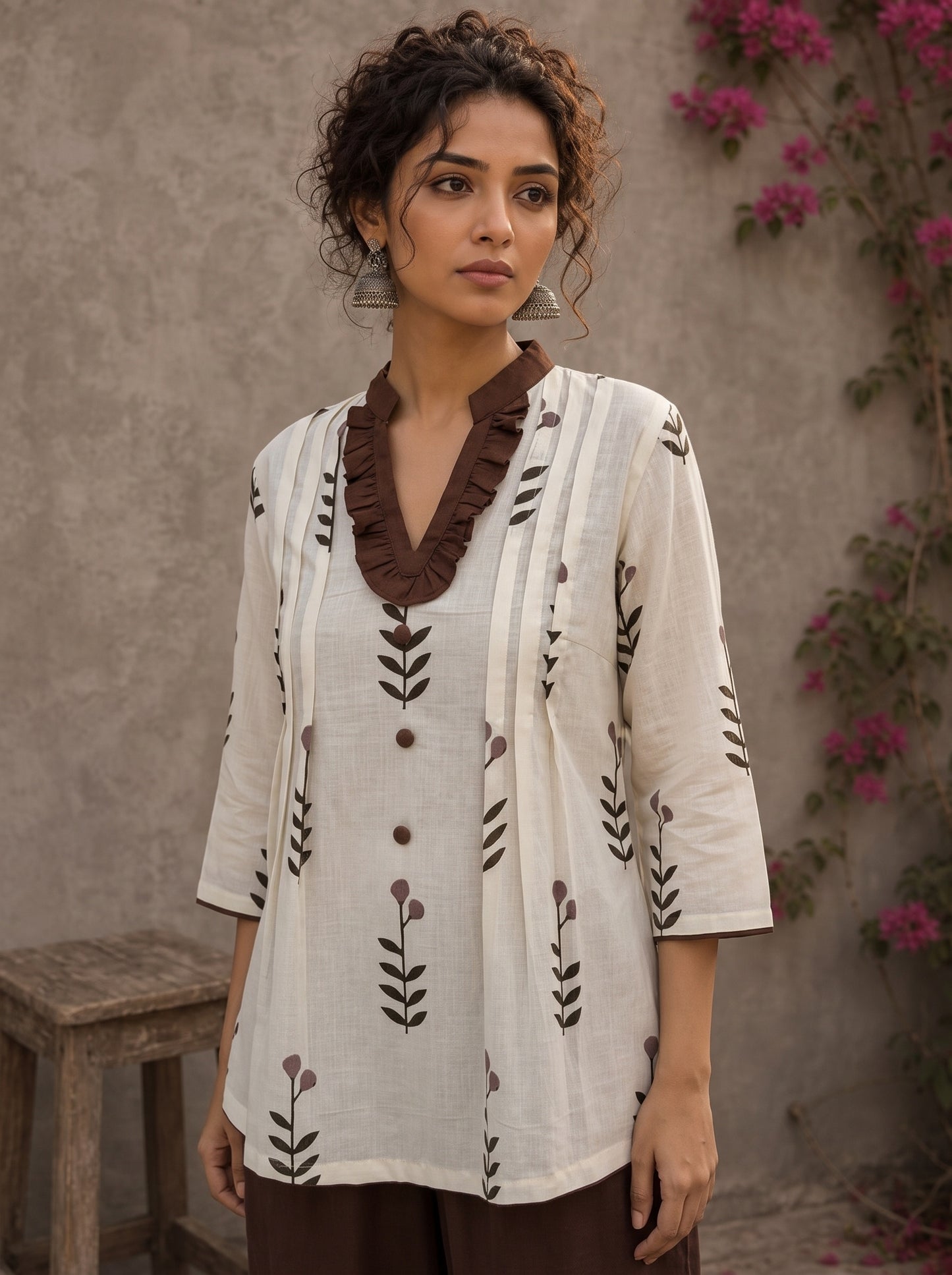 Off-white floral printed top with brown ruffled collar, button front, tie-up sleeves, tassel details, and contrast accents.