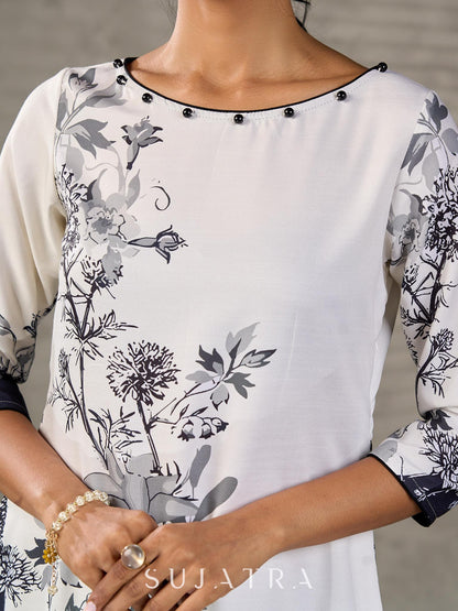 White and black floral dress with pearl embellishments and black accents.