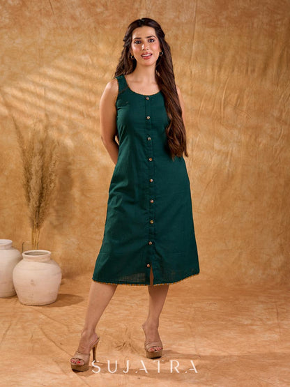 Rich bottle green cotton dress in a straight silhouette, detailed with mustard Ikat buttons and accents, creating a neat, balanced look with a polished, easygoing appeal.