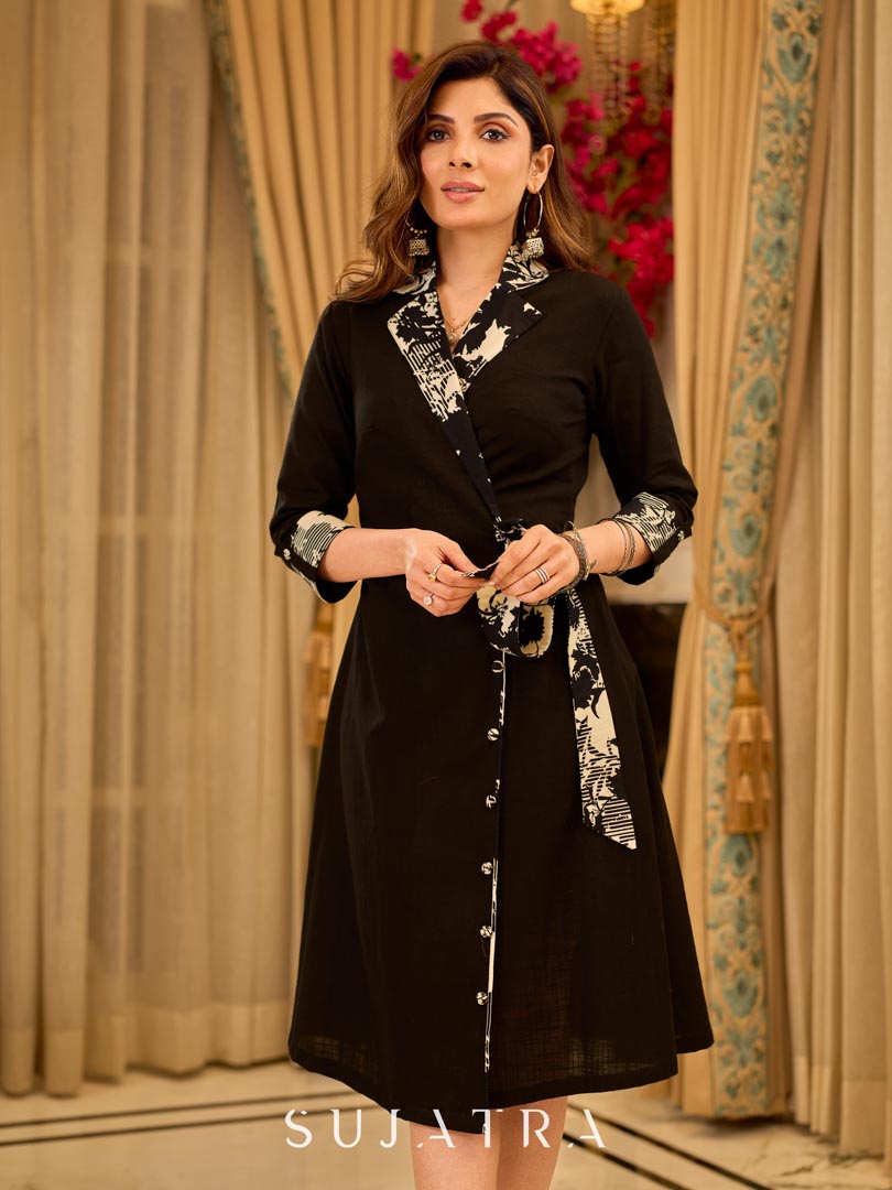 Chic black overlapping blazer-style wrap dress featuring printed black-and-white collar, cuffs, tie detail, and subtle accents