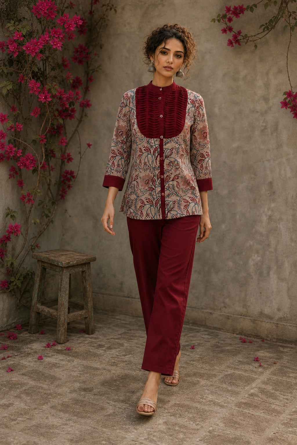 Elegant maroon floral top with intricate maroon pleats, high neckline, covered buttons, and coordinating sleeve cuffs.
