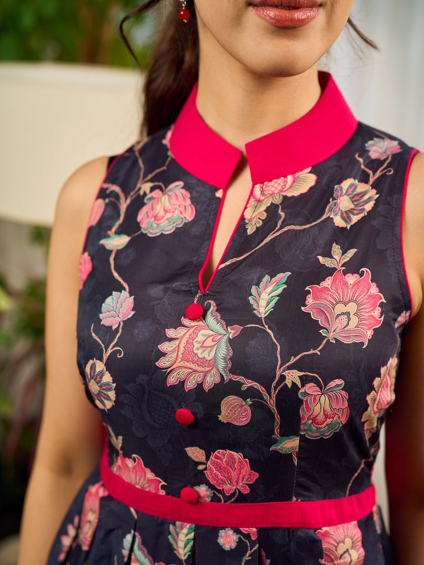 Elegant black Kalamkari dress featuring blooming florals and contrasting pink detailing for refined charm.