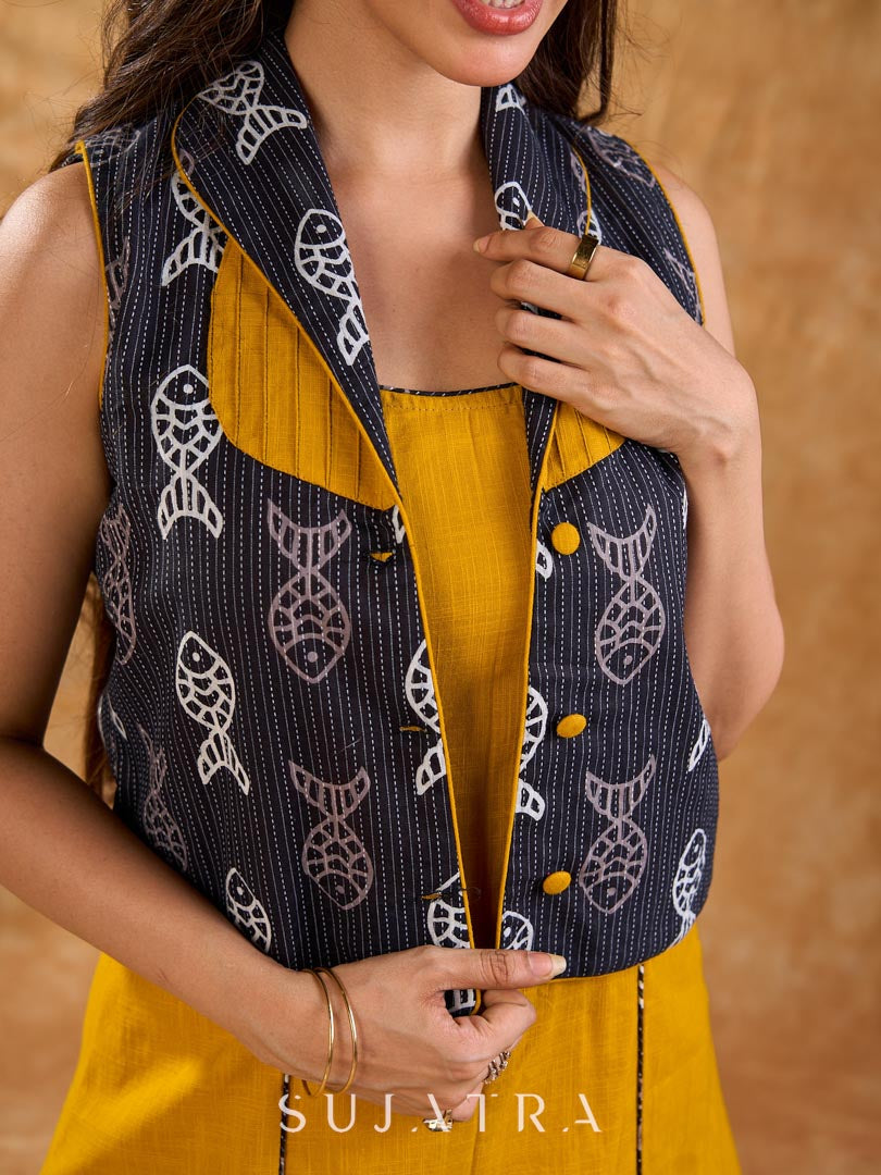 Tailored black Kantha jacket featuring fish motifs, a mustard pintuck patch, and a flipped collar, offering a structured silhouette with refined detail and distinctive, contemporary character.