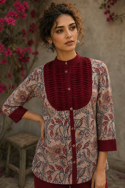 Elegant maroon floral top with intricate maroon pleats, high neckline, covered buttons, and coordinating sleeve cuffs.