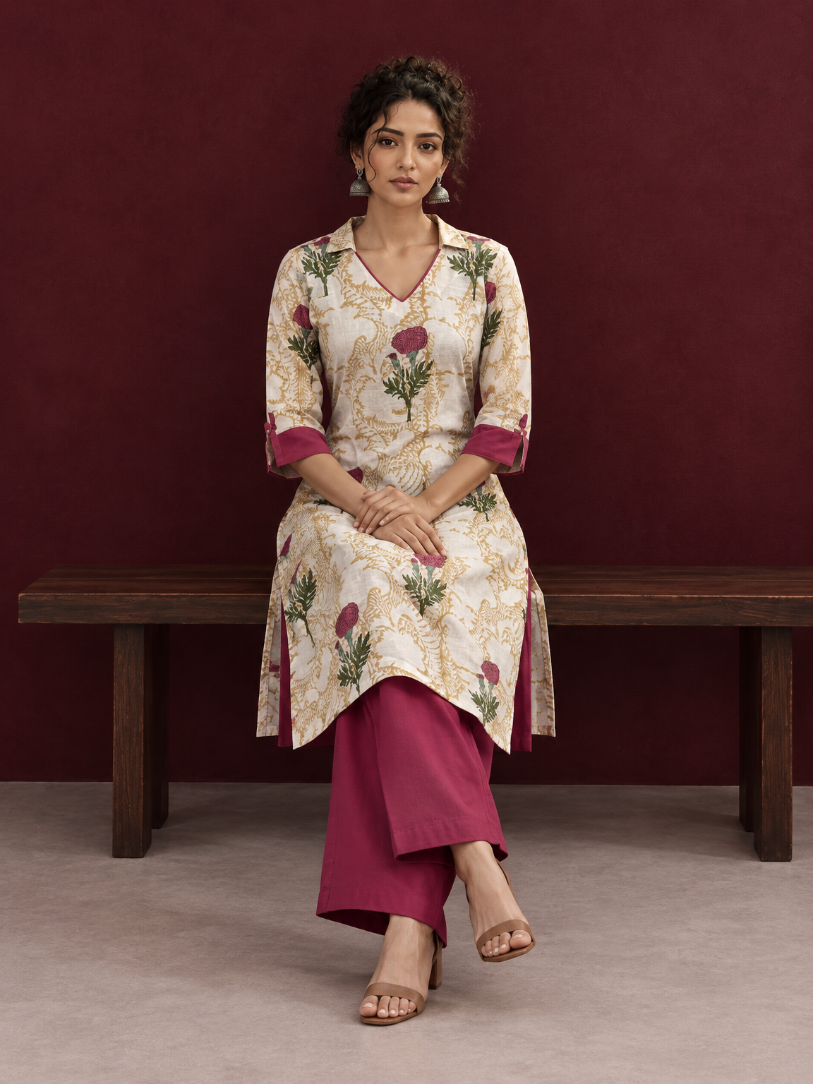 Ivory floral printed kurta with pink and green flowers, a V-neck, and contrasting pink cuffs. — seated
