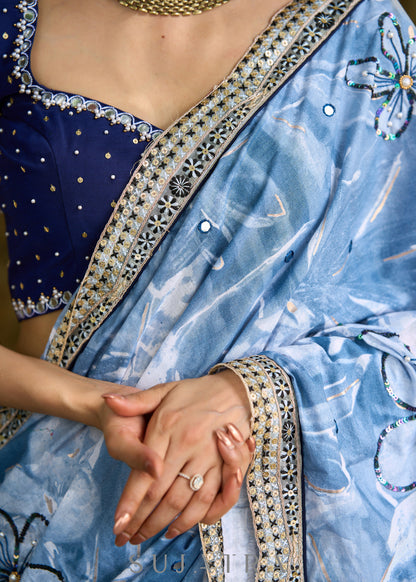 Stylish sky blue floral printed saree highlighted with sequence embroidery & contrast embroidered lace