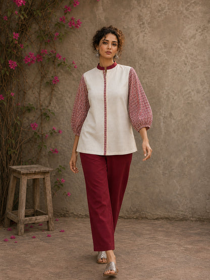 Chic off-white top featuring intricate hand block print sleeves in a vibrant red, complemented by a matching central decorative trim.