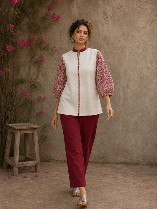 Chic off-white top featuring intricate hand block print sleeves in a vibrant red, complemented by a matching central decorative trim.