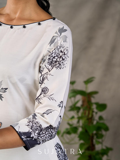White and black floral dress with pearl embellishments and black accents.