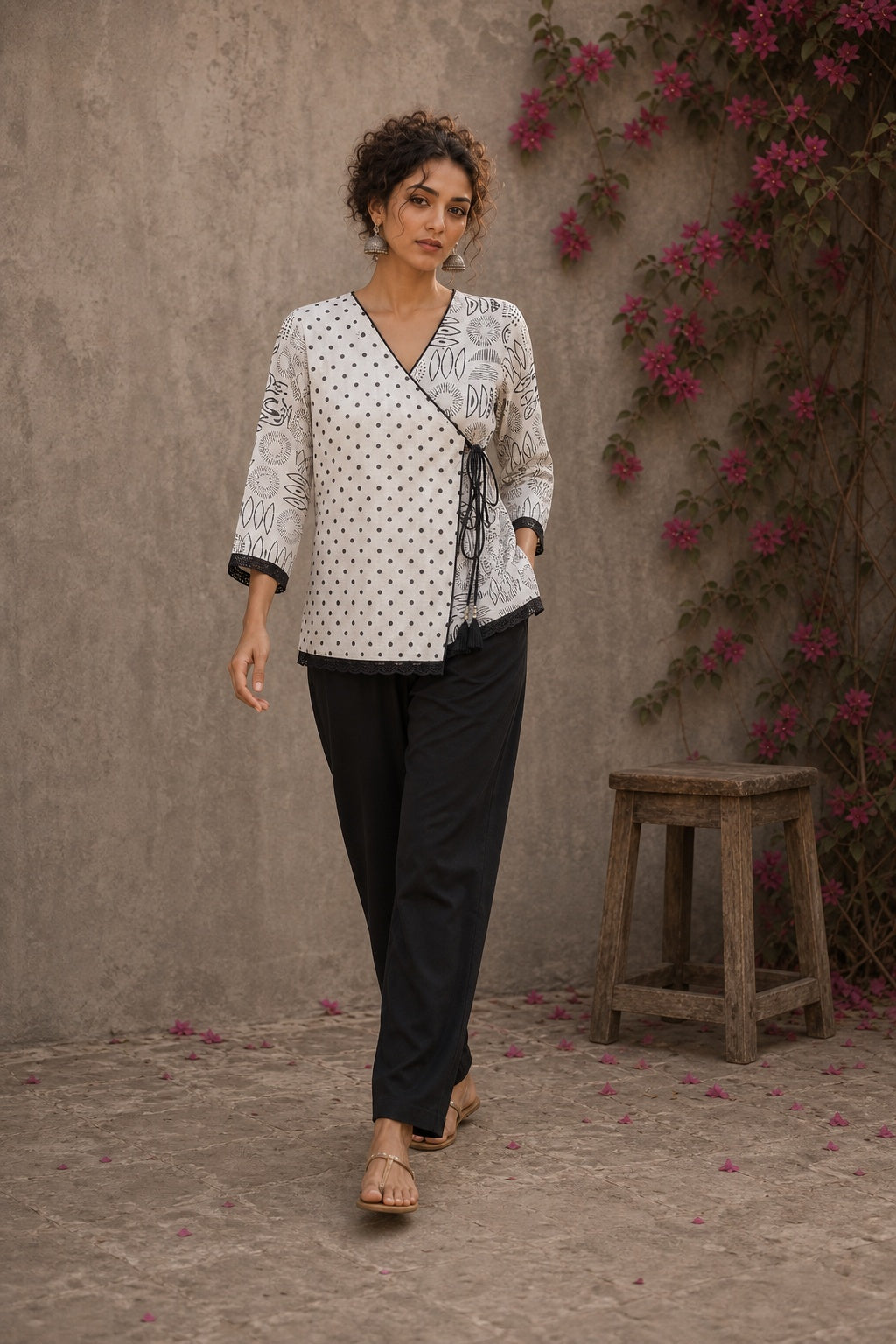 Black and white printed crossover top with contrast polka dots, lace-trimmed sleeves, side tie, tassels, and scalloped hem.