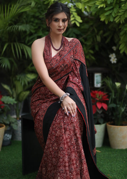 Dussehra Sale — Sensuous maroon Ajrakh saree with black border & Accentuated with stone embellishment.