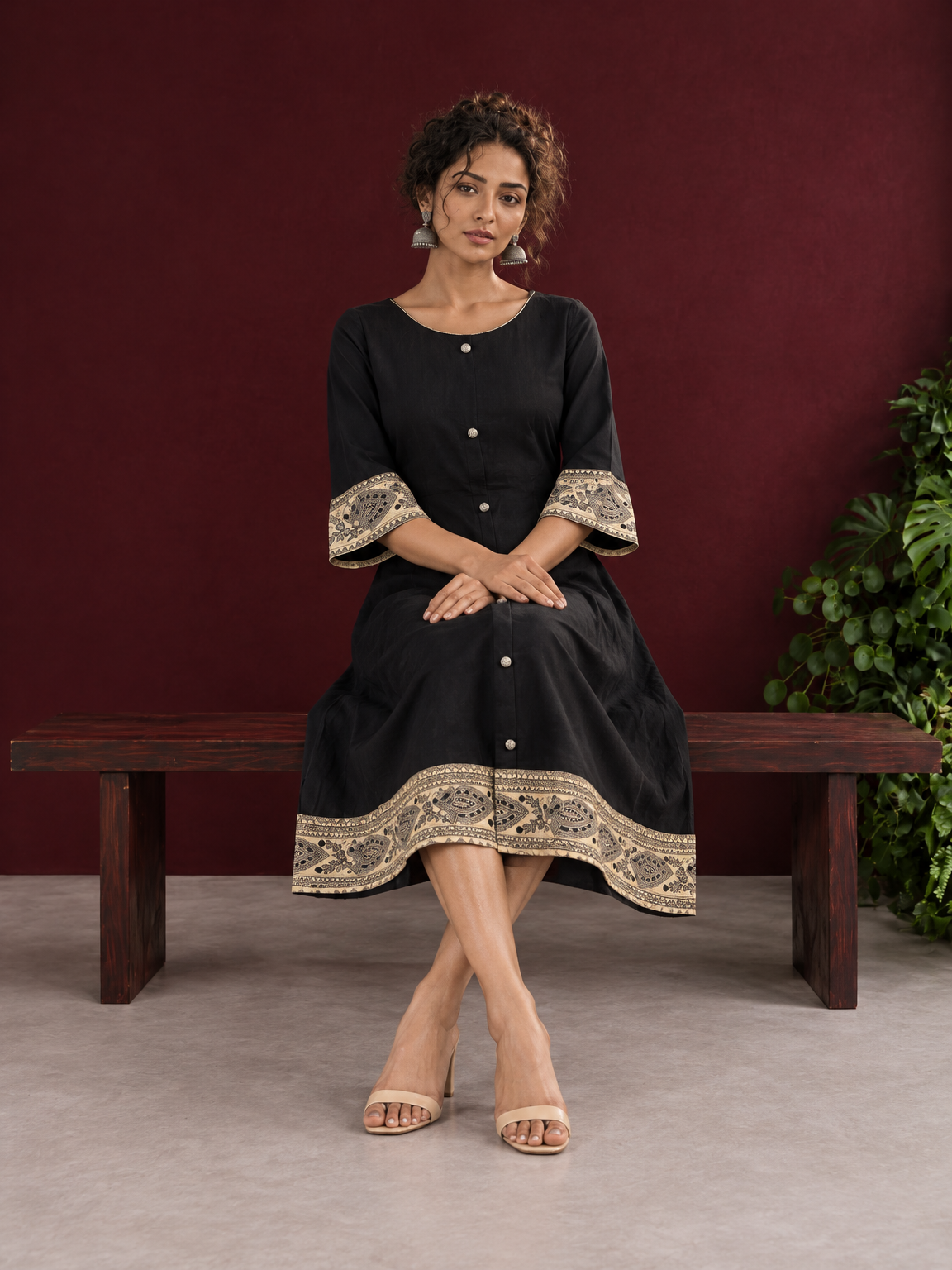 Elegant Black Cotton A-Line Dress with Madhubani Print Border Hem and Matching Bell Sleeve Cuffs — seated — view 2