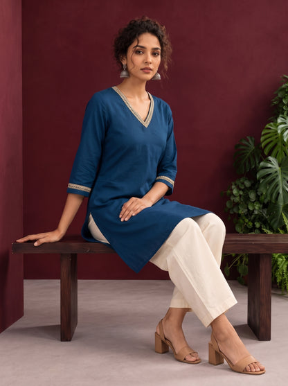 Elegant Teal Blue Cotton Tunic with Embellished Gold Lace V-Neckline and Matching Sleeve Cuffs — seated