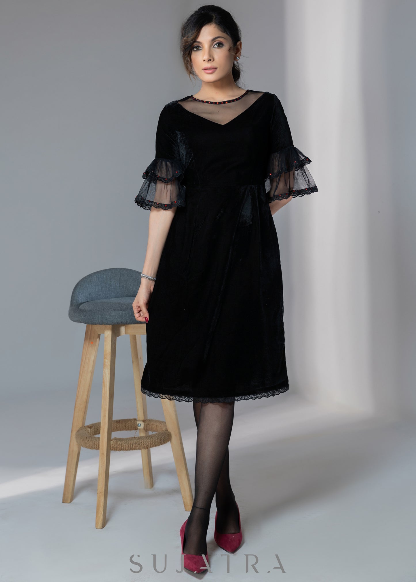 Party wear black velvet dress with net sleeves & red stone work detailing on the neck