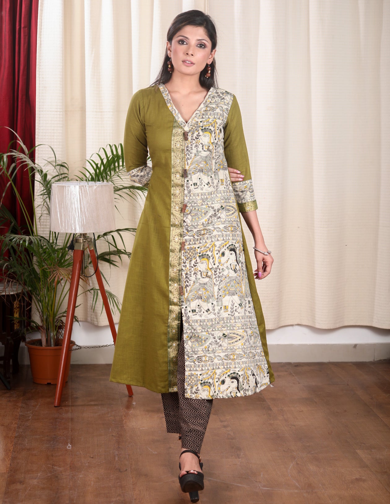 A Line Cotton Mehndi Green Kurta With Classy Madhubani print and Zari Border and Wooden Beads.
