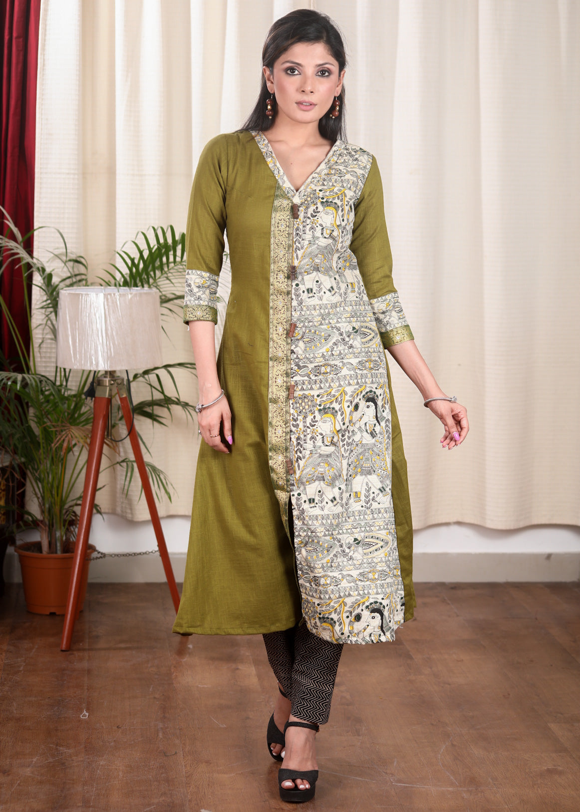 A Line Cotton Mehndi Green Kurta With Classy Madhubani print and Zari Border and Wooden Beads.