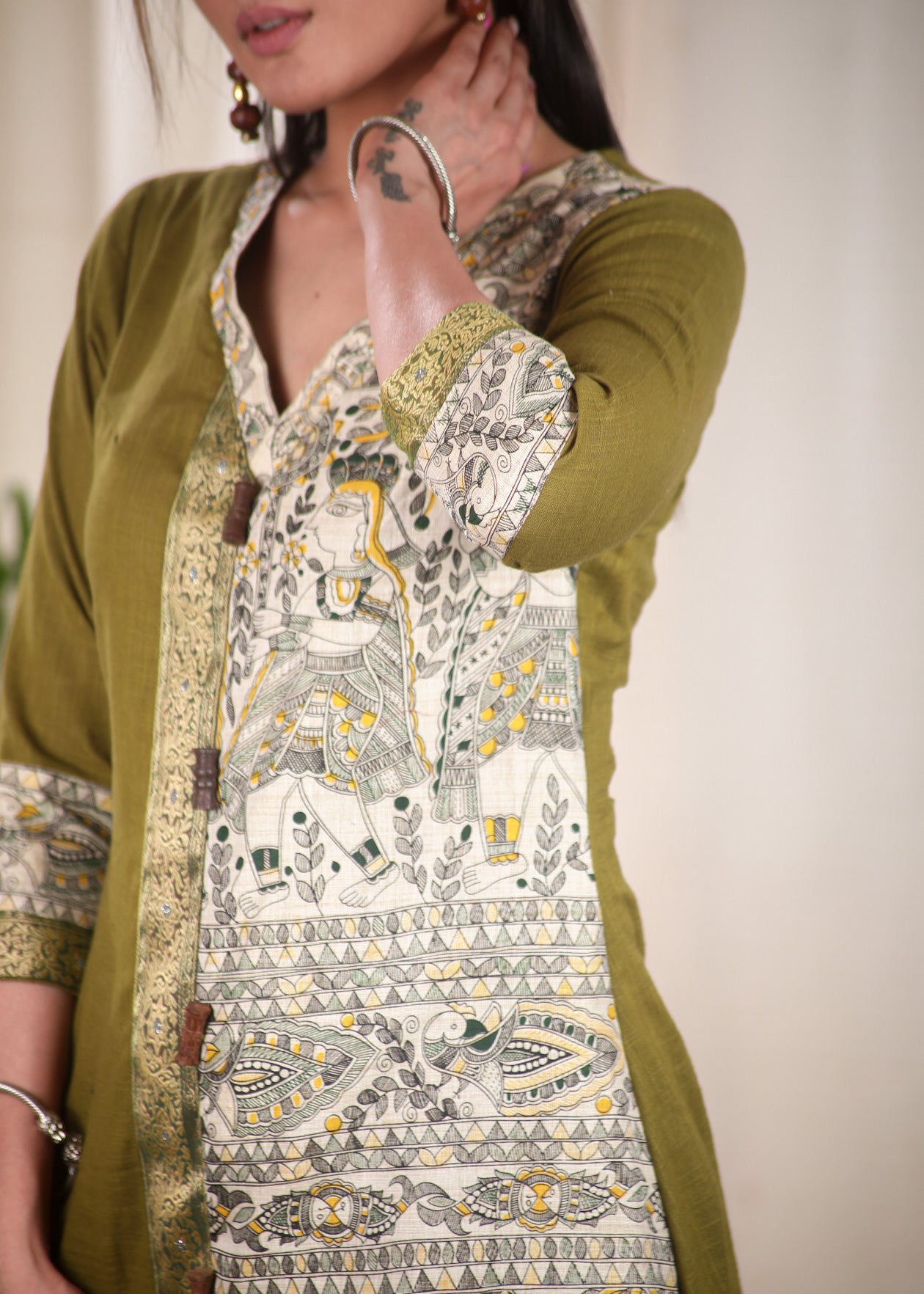 A Line Cotton Mehndi Green Kurta With Classy Madhubani print and Zari Border and Wooden Beads.