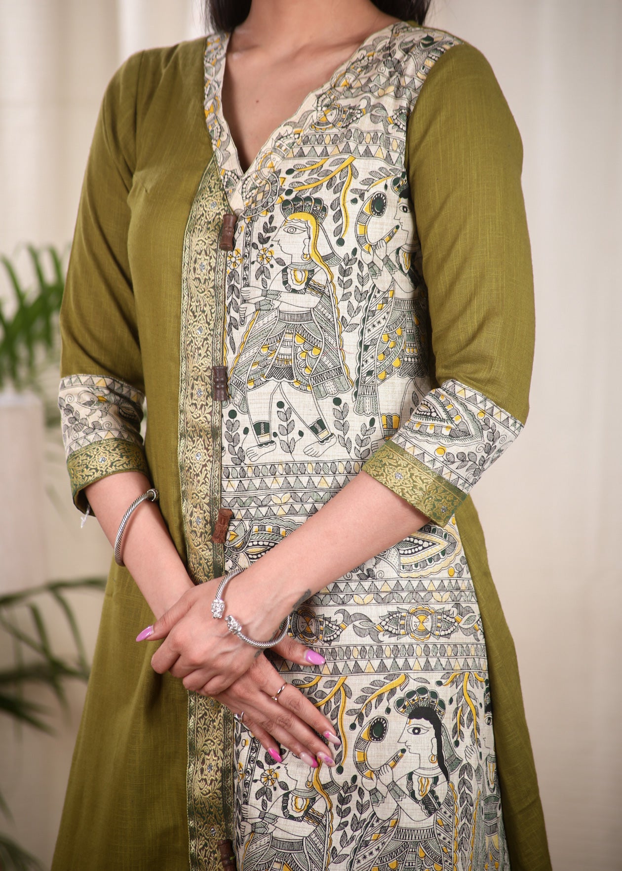 A Line Cotton Mehndi Green Kurta With Classy Madhubani print and Zari Border and Wooden Beads.