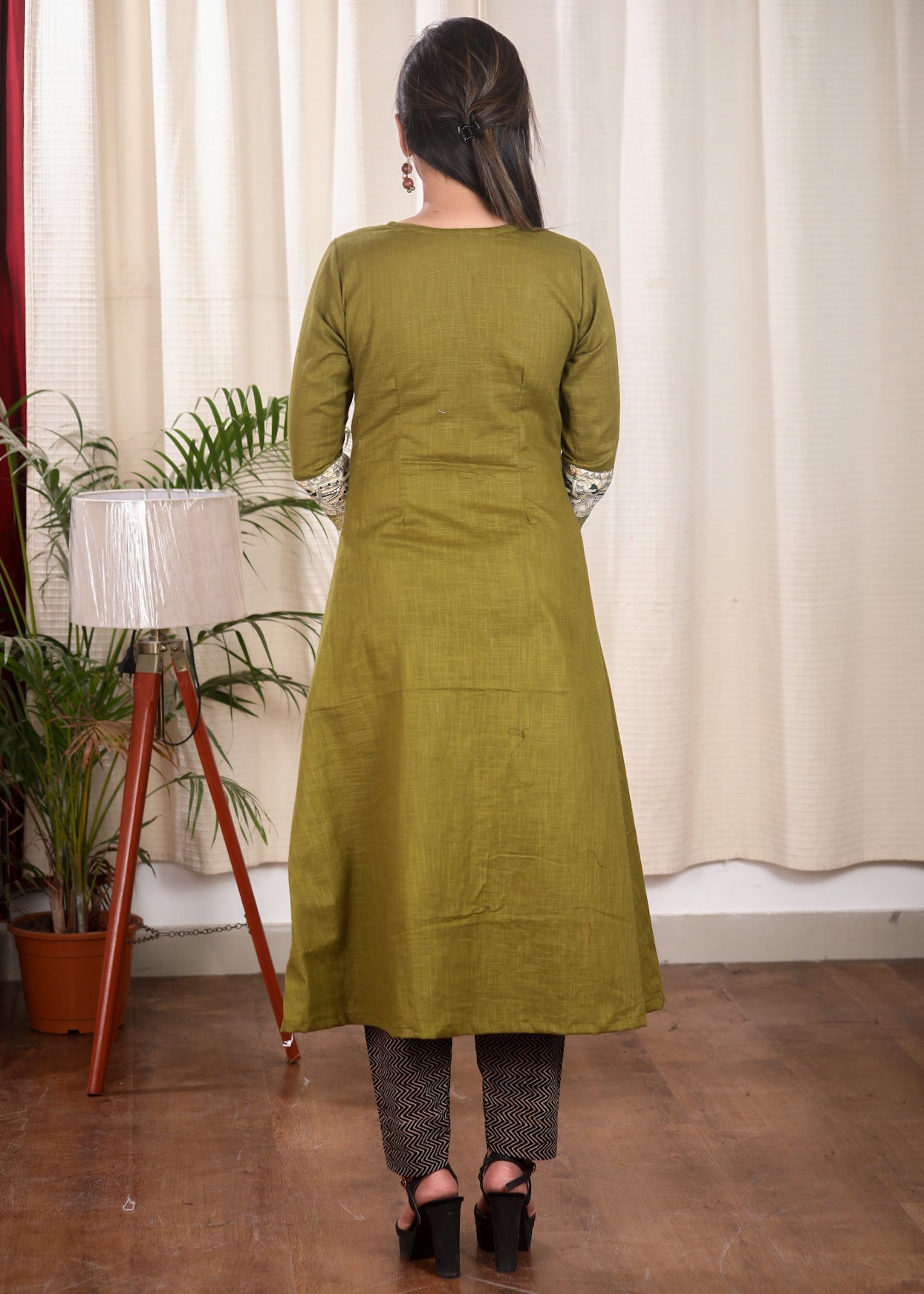 A Line Cotton Mehndi Green Kurta With Classy Madhubani print and Zari Border and Wooden Beads.