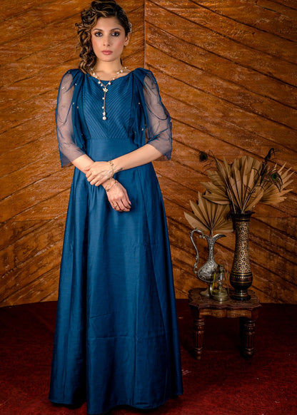 Blue satin gown with net sleeves, sequence work & self tucks on yoke.